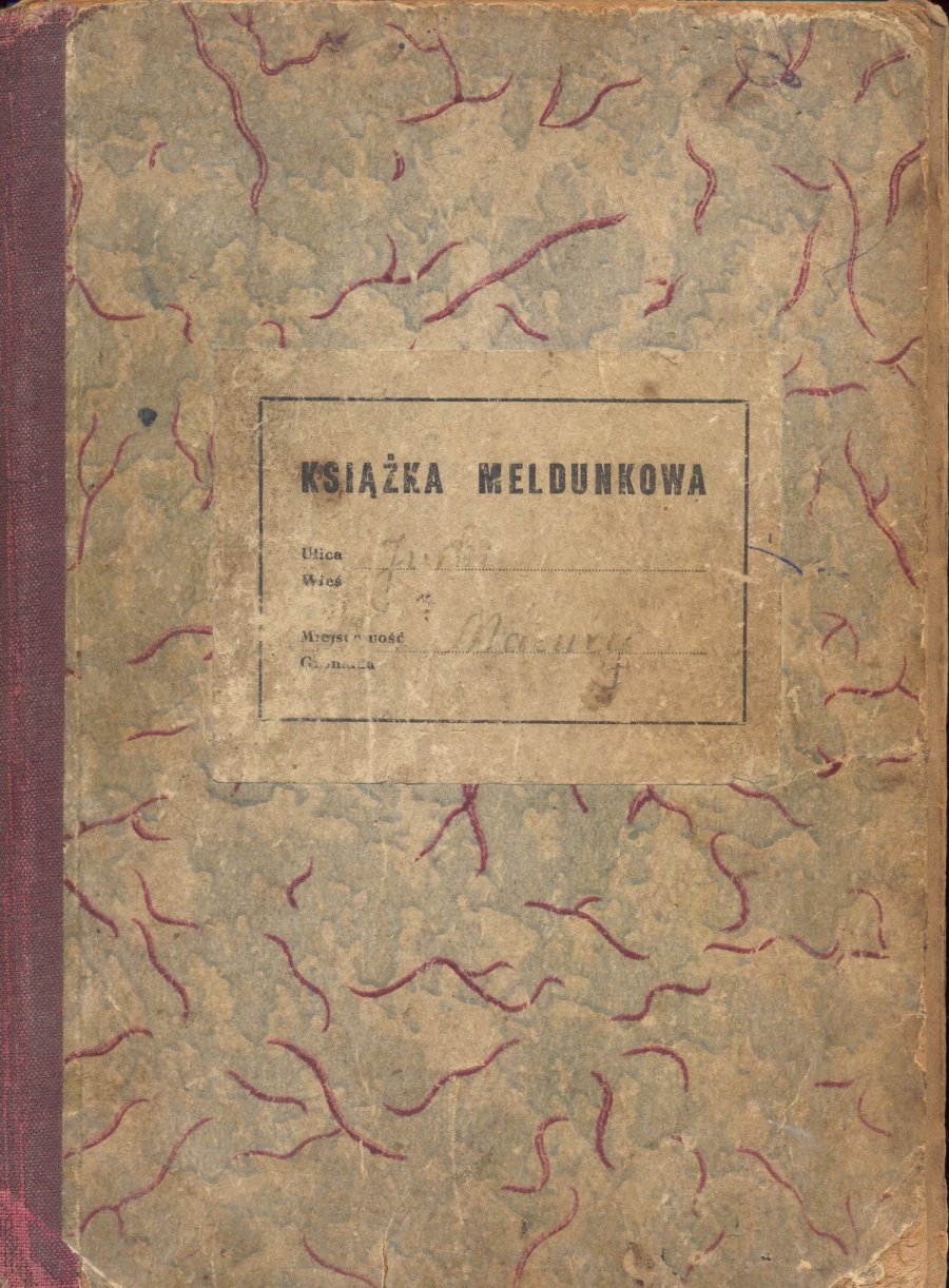 Stara okładka książki meldunkowej z napisem „KSIĄŻKA MELDUNKOWA”. Widoczna jest ręcznie dopisana nazwa wsi „Jurki” i miejscowość „Mazury”. Okładka ma zużyty wygląd z kolorowym, marmurkowym wzorem i czerwoną grzbietówką.